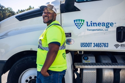 Smiling driver in high-visibility vest standing beside a Lineage Transportation truck, representing the dedicated workforce behind efficient food supply chain logistics.